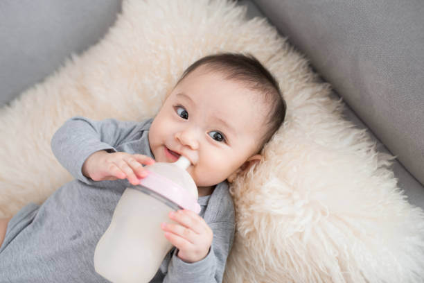 asian baby infant eating milk from bottle, 9 months after birth