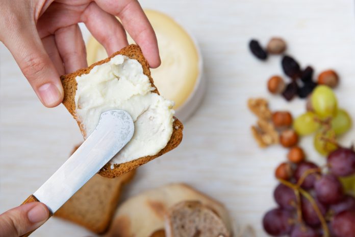 woman spreading soft cheese toasted bread